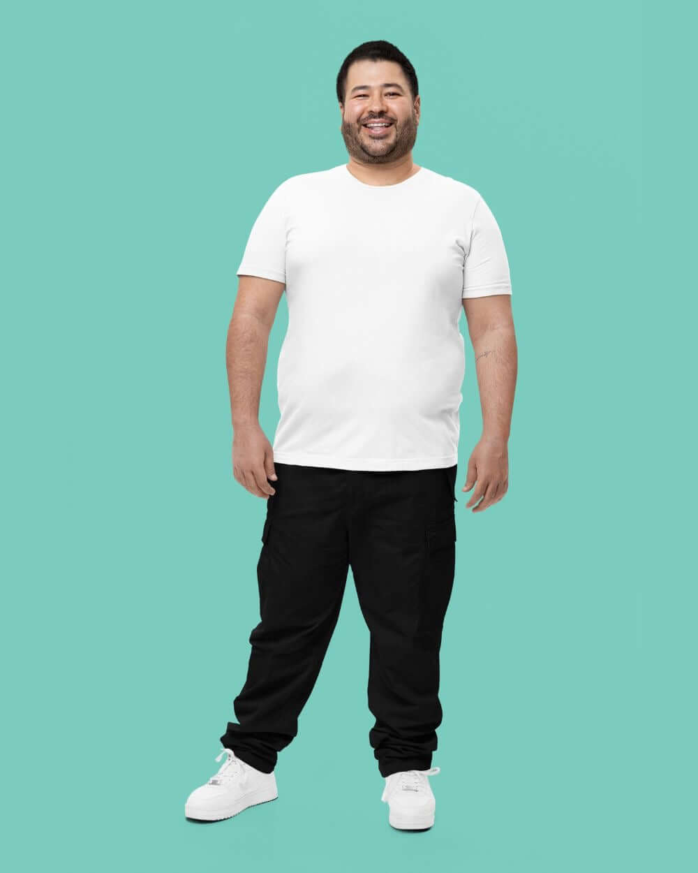 Man in a white t-shirt and black pants, showcasing casual comfort and style against a teal background.